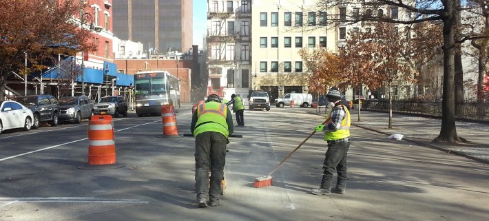 DOT crews at work yesterday morning, erasing part of the pedestrian space on Mount Morris Park West. Photo: Stephen Miller