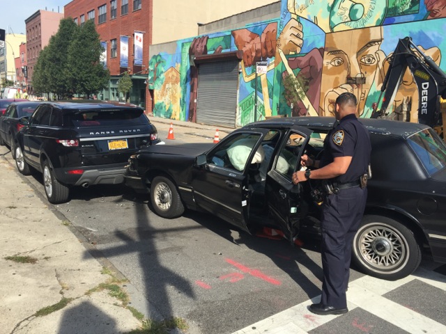 An officer from the 78th Precinct inspects the vehicle on Degraw Street after its driver fled yesterday morning. Photo: Mike Donohue