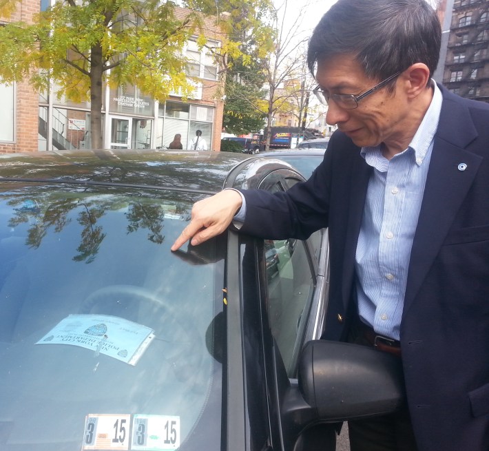 Wellington Chen of the Chinatown Partnership LDC points to a placard parker who left his car on the street all day. Photo: Stephen Miller