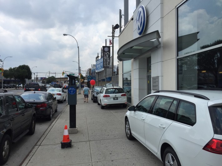 Muni meter? Sidewalk? Nothing can stop this Northern Boulevard car dealership from displaying its wares. Photo: Clarence Eckerson Jr.