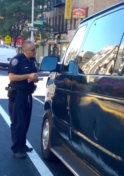 A 34th Precinct officer cites a driver blocking a bike lane on Sherman Avenue in Inwood. Photo: 34th Precinct/Facebook