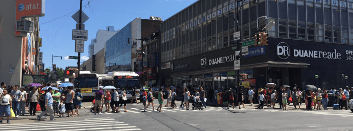 Pedestrians crossing Roosevelt Avenue at Main Street, the location of the Flushing-Main Street subway station, at around noon today. Photo: David Meyer