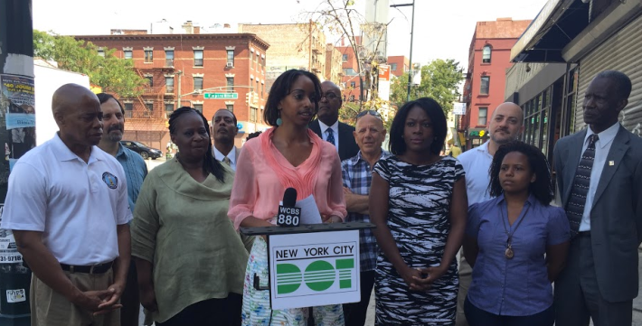 Nostrand Avenue Merchant Association Vice President Pia Raymond speaks alongside Assembly Member Diana Richardson (right) and Brooklyn Borough President Eric Adams (far left). Photo: David Meyer