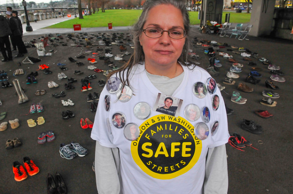 Kristi Finney, who lost her son Dustin when a truck driver hit him from behind while biking, stands before 421 pairs of shoes symbolizing each person killed in traffic in Oregon so far this year. “The average person is indifferent to this until it happens to them,” she told Bike Portland.