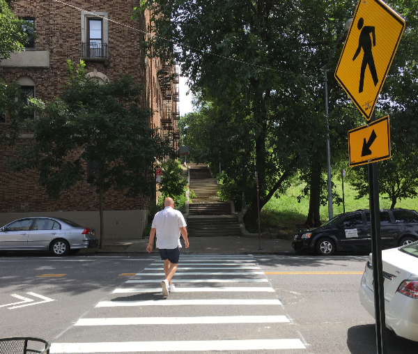 Fresh stripes replace an unmarked crosswalk on Seaman Avenue at W. 214th Street, between Inwood Hill Park and Isham Park.
