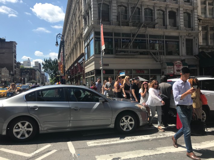 Pedestrians are forced to walk around cars in the crosswalk at 23rd and Sixth Avenue. Photo: Julianne Cuba.