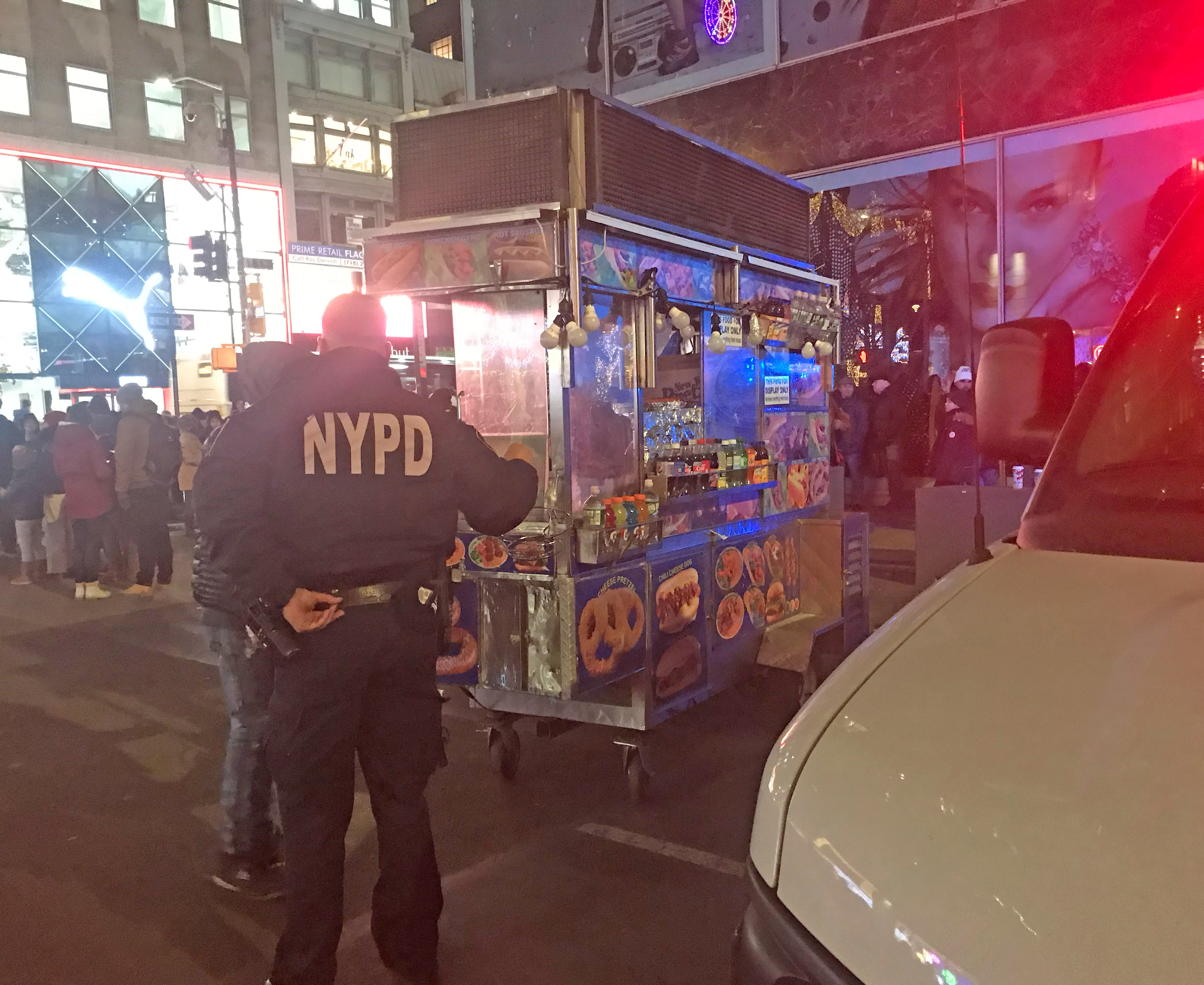 A cop tells a vendor he can't bring his food truck down 50th Street. Photo: Julianne Cuba