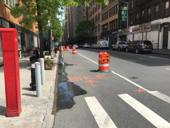 Good luck understanding what this spray paint and barrel setup on 38th Street and Eighth Avenue means. Photo: Dave Colon