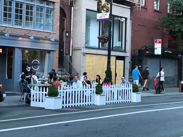 Diners on 8th Street protected by a white picket fence. Photo: Janet Liff