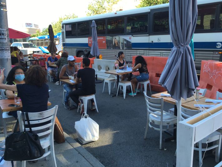 People eat next to a passing express bus at Cocina Chente on Riverdale Avenue. Photo: Eve Kessler