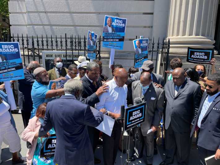 A group of faith leaders in Harlem place their hands on Eric Adams, their candidate for mayor.
