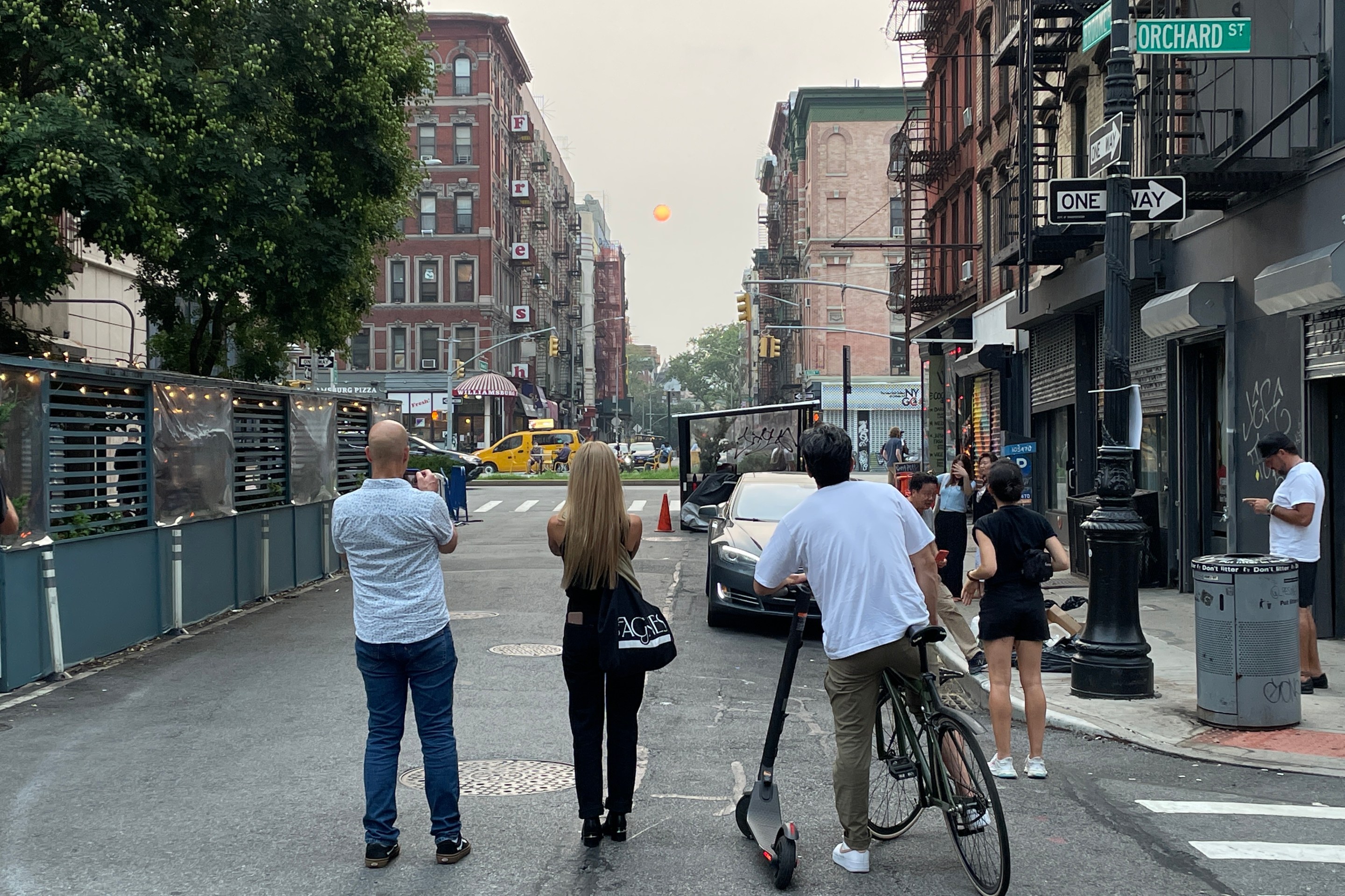 People on the street take photos of a blood red sun created by smoke from Oregon's wildfires.