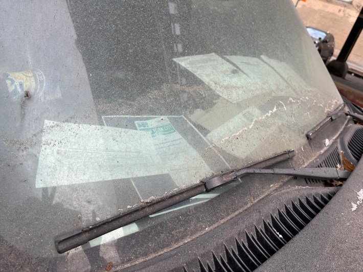 Papers from the DOT and the DMV litter the dash of an abandoned SUV on Tenth Avenue. Photo: Eve Kessler