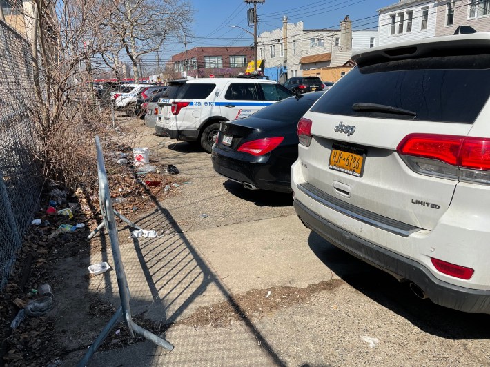 Most of the sidewalk cut off by cars parked outside the 69th Precinct.