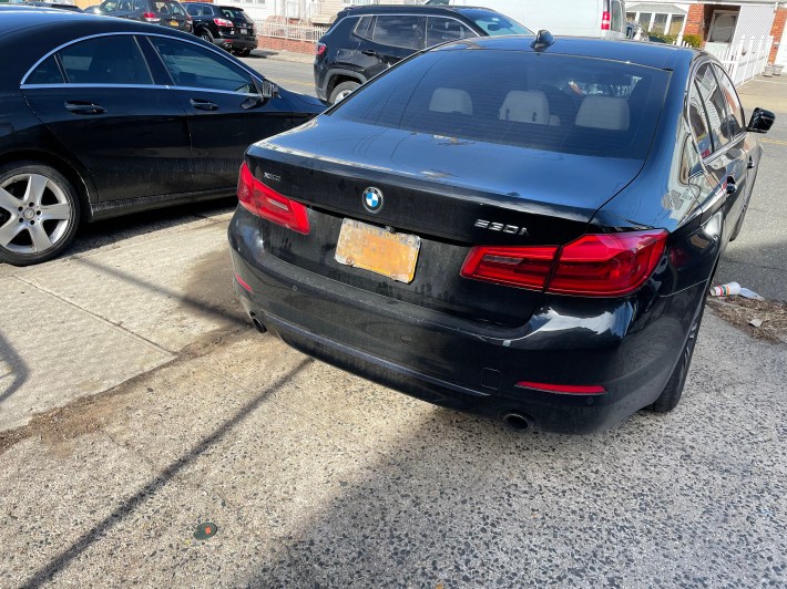 A car parked on the sidewalk next to the 69th Precinct with license plate with a cover to avoid tolls and tickets. Photo: Dave Colon