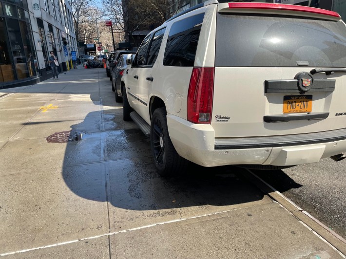 A row of cars parked half on the sidewalk on Johnson Street, around the corner from the 84th Precinct.