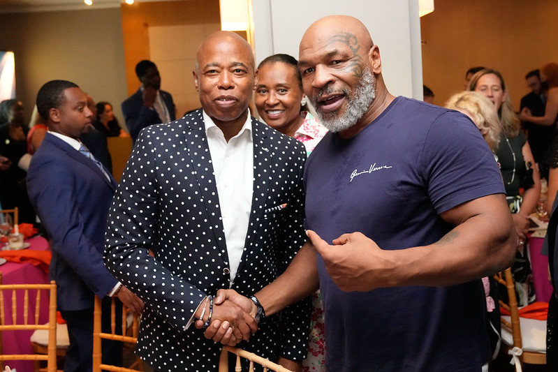 NYC Mayor Eric Adams, wearing a black polka dotted suit, poses with Mike Tyson.