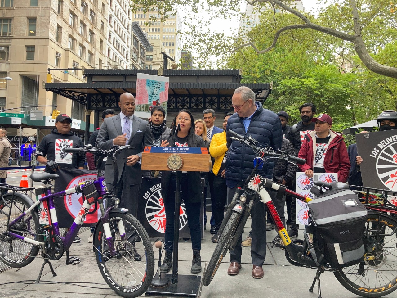 Ligia Guallpa with Sen. Chuck Schumer and Mayor Adams in announcing plans to turn vacant newsstands, like the one behind them, into charging hubs for delivery workers last October. Photo: Julianne Cuba
