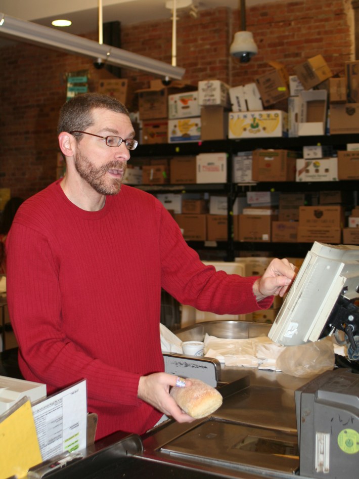 A man uses a checkout machine to add up the cost of groceries.